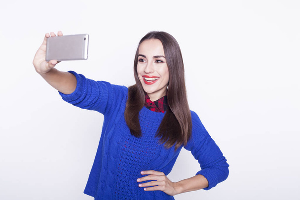 Beautiful young girl with a phone makes selfie. - Foto, immagini