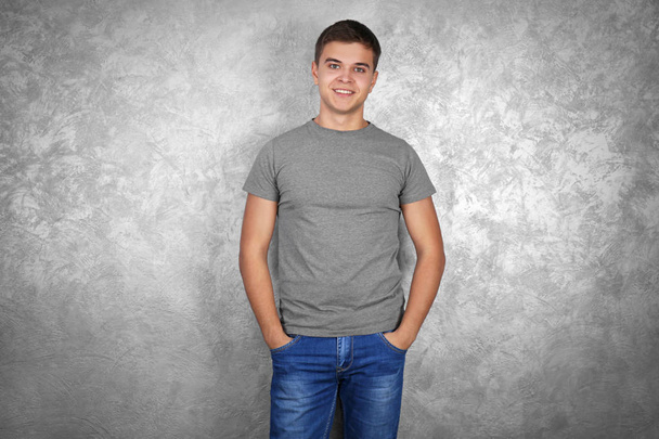 Beau jeune homme en t-shirt blanc gris debout contre un mur texturé
 - Photo, image