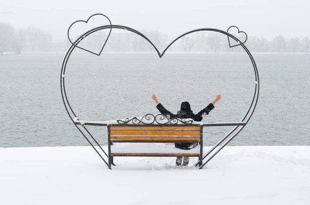 K nepoznání dívka sedící na lavičce krásné tepané železo lásky v parku s jezírkem a užívat si krásné zimní den v samotě. - Fotografie, Obrázek
