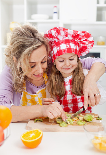 Woman and little girl making fresh fruits snack together - Foto, afbeelding