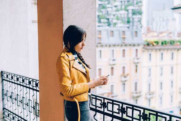 женщина опирается на балкон с помощью смартфона
 - Фото, изображение