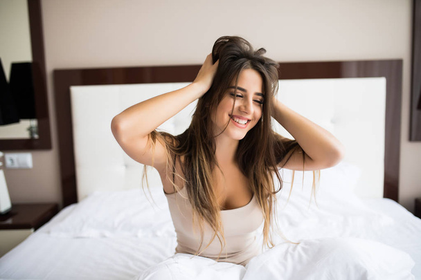Γυναίκα χαμόγελο και το τέντωμα στο κρεβάτι  - Φωτογραφία, εικόνα
