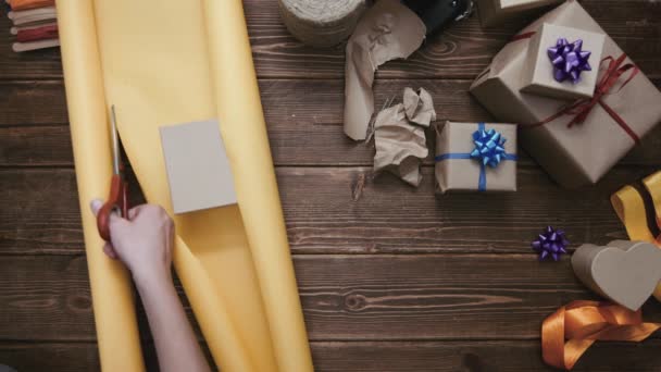 Person schneidet Papier und verpackt Geschenk - Filmmaterial, Video