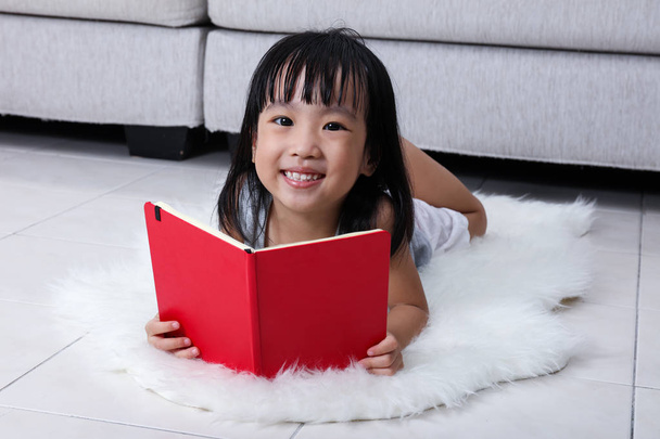Happy Asian Chinese little girl reading book on the floor - Фото, зображення