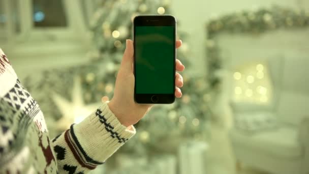 Zbliżenie: kobiecych rąk dotykając zielonego ekranu na telefon komórkowy. Kluczowanie. Z bliska. Śledzenie ruchu. Vertical.with rozmycie tła Dekoracje świąteczne - Materiał filmowy, wideo