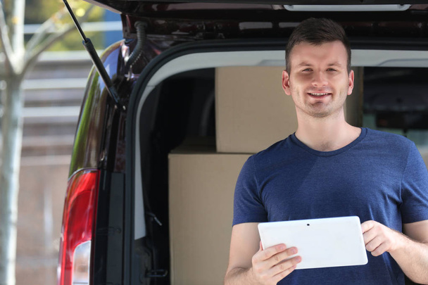 Male deliverer with tablet beside car - Fotografie, Obrázek