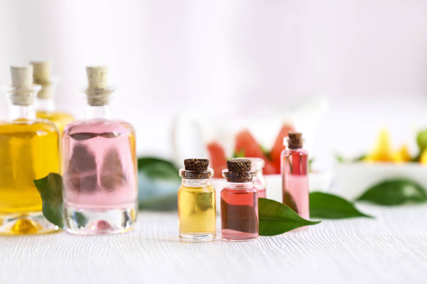 Bottles with essential oil and leaves on wooden table - Photo, Image