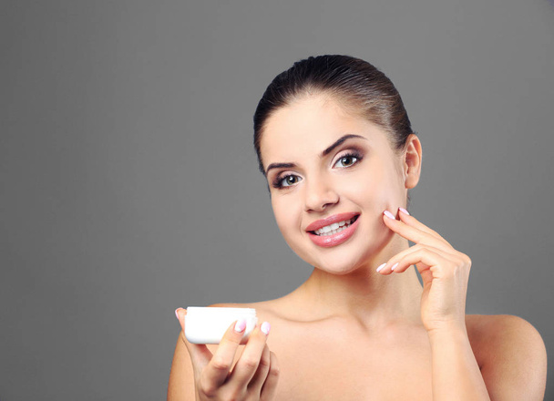 Beautiful young woman applying cream onto face - Foto, immagini