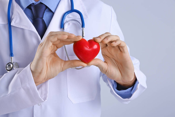 Male doctor hands holding red heart on light background - Photo, Image