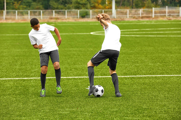 Boys playing football at stadium - Foto, Bild