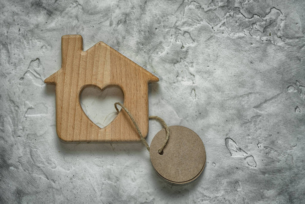 Maison de jouet en bois avec une étiquette vierge sur fond de ciment comme symbole de l'hypothèque
 - Photo, image