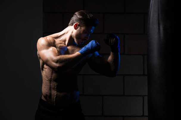 MMA Fighter Practicing With Boxing Bag - 写真・画像