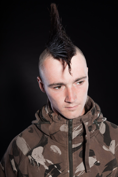 Punk man with mohawk haircut. Expressive face. Army camouflage jacket. Isolated on black background. Studio shot. - Photo, Image