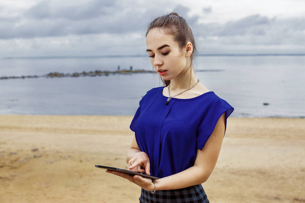 Beautiful girl with long brown hair holding a tablet computer. - Fotó, kép