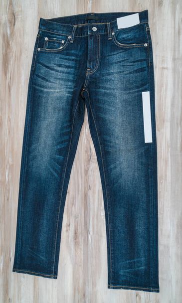 Blue jeans with price tag on  wooden background . - Φωτογραφία, εικόνα
