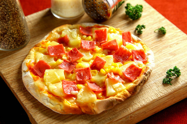 Schinken und Ananas-Pizza auf Holztisch - Foto, Bild