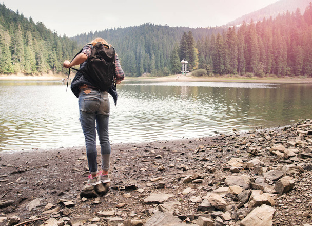 Young woman stands near a mountain lake enjoying the moment - Foto, imagen