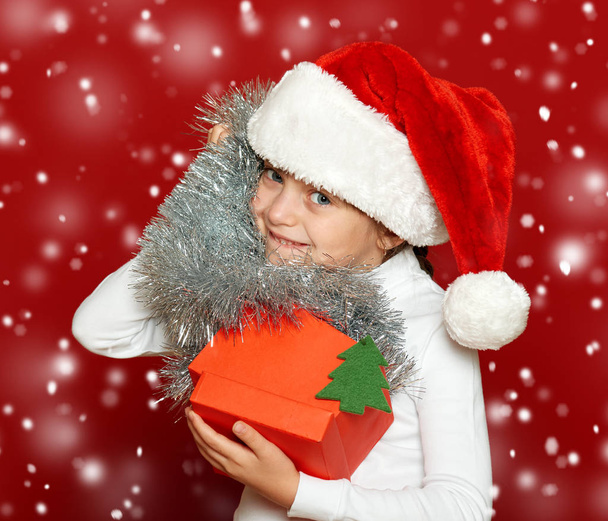 Mädchen-Porträt mit Geschenkschachtel auf Rot, Weihnachtsferien-Konzept - Foto, Bild