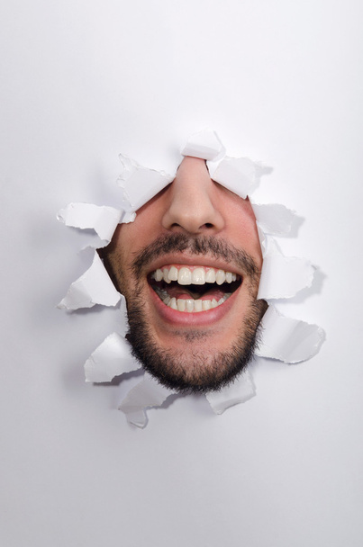 Cara masculina a través del agujero en papel - Foto, imagen