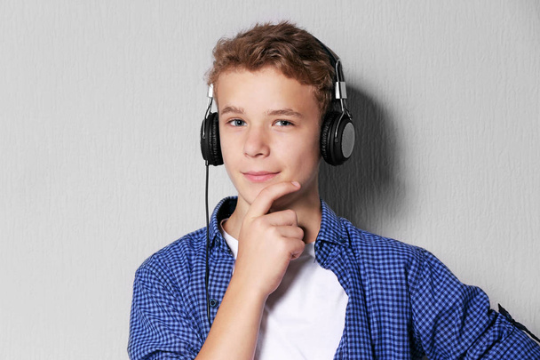 Boy listening music on light background - Фото, изображение