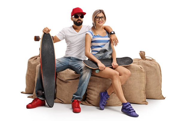 Skaters with a longboard and a skateboard sitting on burlap sack - Fotoğraf, Görsel