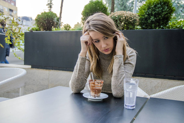 Portrait of depressed teenage girl sitting in coffee shop. Depressed woman in the coffee shop. Sad and depressed woman alone in a lonely bar - Photo, image
