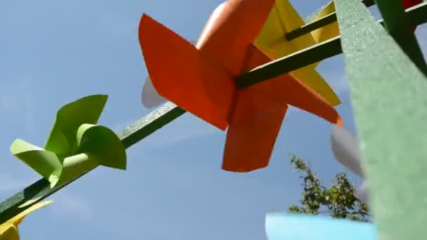 kleurrijke papier windmolens op lucht en wind - Video