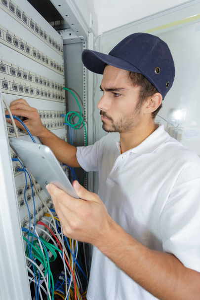 focused electrician applying safety procedure while working on electrical panel - Фото, изображение