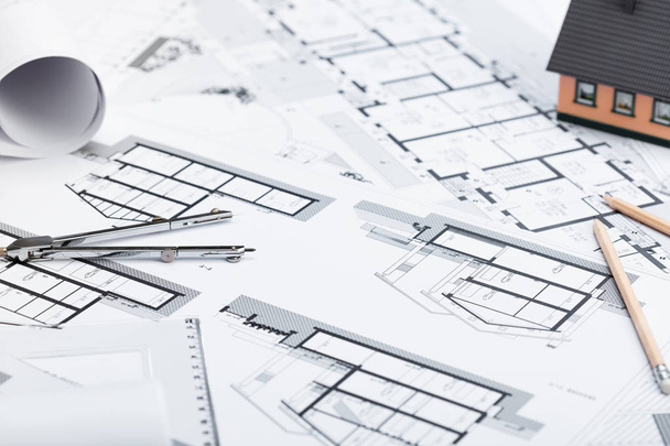 Planos de construcción con herramientas de dibujo y casa en miniatura en blu
 - Foto, Imagen