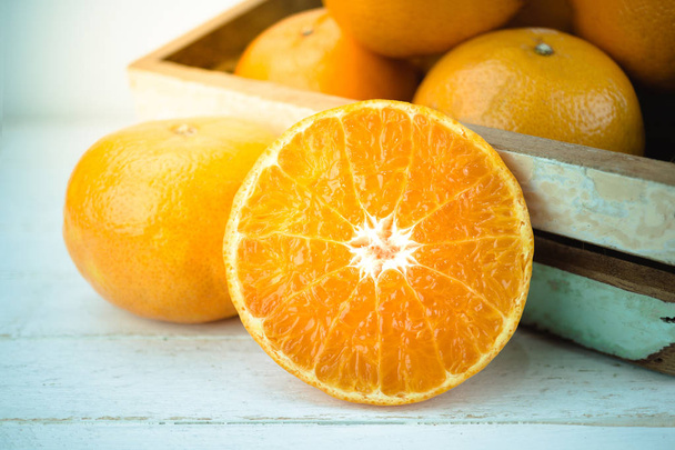 Orangen, ganze Orangenfrüchte und in Scheiben geschnittene Orange auf Holz  - Foto, Bild