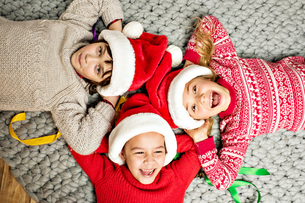 děti v Santa klobouky leží v kruhu - Fotografie, Obrázek