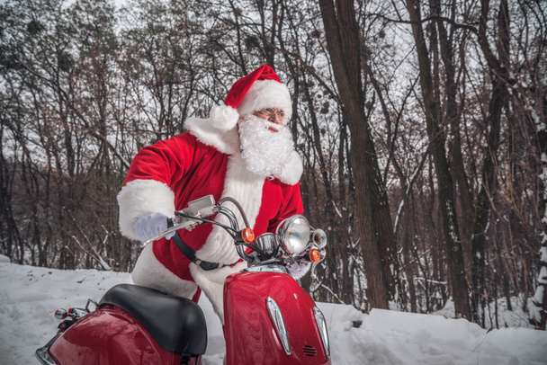 Санта Клаус сидит на красном скутере
 - Фото, изображение