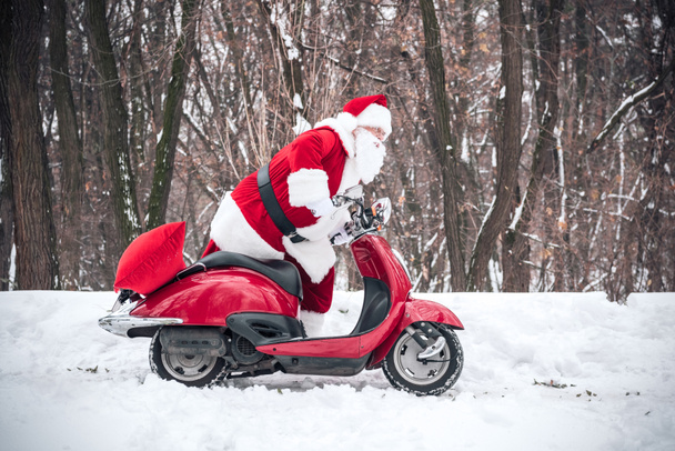 Santa Claus paardrijden rode scooter - Foto, afbeelding