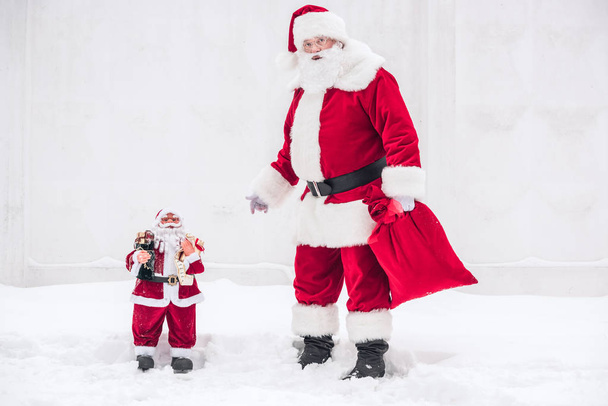 Санта Клаус стоит рядом с Маленьким Сантой
    - Фото, изображение