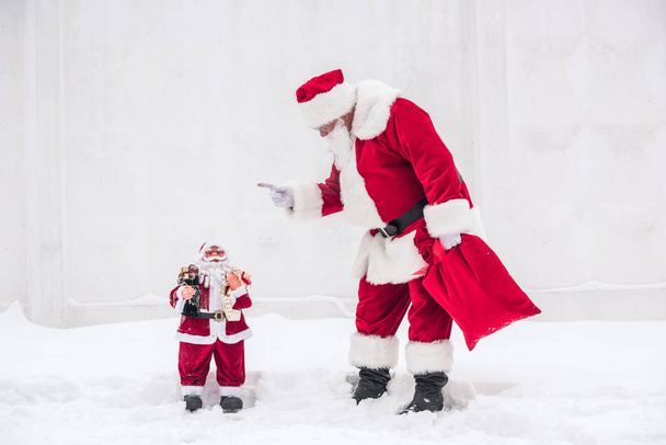 Papai Noel repreendendo o pequeno Papai Noel
   - Foto, Imagem