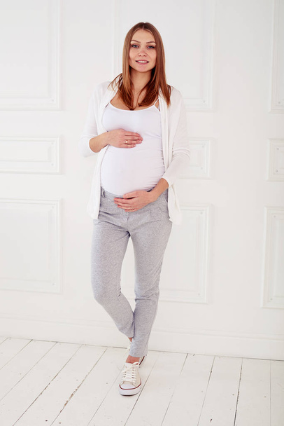 Full-length portrait of young beautiful pregnant woman touching  - Foto, Bild