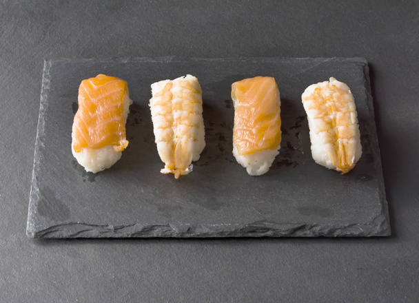 Pieces of sushi on a black stone - Foto, afbeelding
