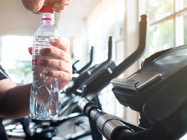 fat man hands opening bottle of water on exercise bike - 写真・画像