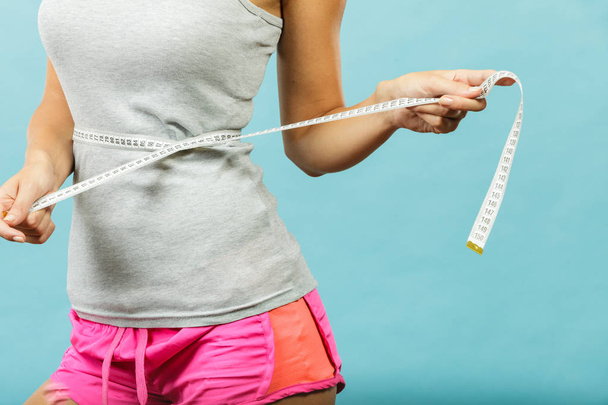 Fitness girl measuring her waistline - Foto, Imagen