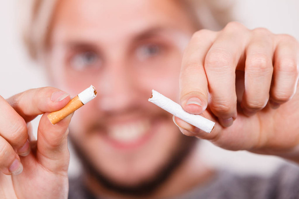 Lächelnder Mann zerbricht eine Zigarette - Foto, Bild