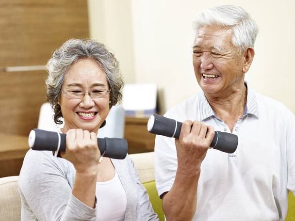 senior asian couple exercising using dumbbells - Photo, Image