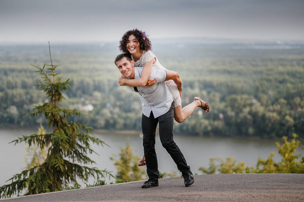 retrato de atractivo caucásico joven pareja piggybacking al aire libre
. - Foto, Imagen