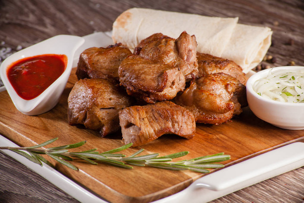 pork skewers on a wooden board in a white dish with pickled onio - Фото, изображение