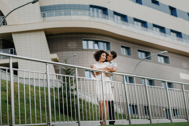 Jeune couple étreignant dans la ville au grand bâtiment
 - Photo, image