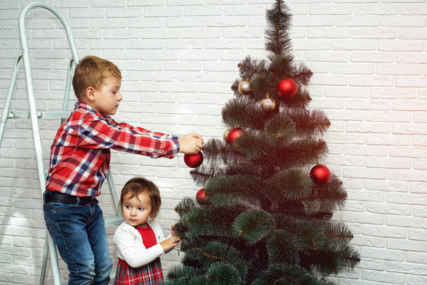 kauniit pienet lapset koristavat joulukuusen. Hyvää joulua.
 - Valokuva, kuva