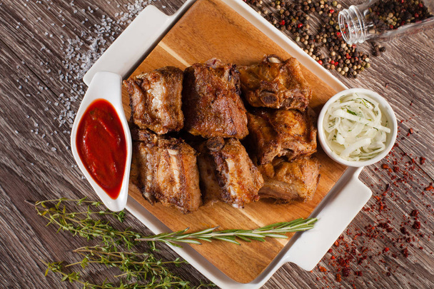 pork ribs grilled on a wooden board with a white plate, scattere - Фото, зображення