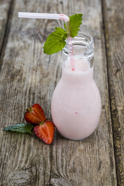 Smoothies and ripe strawberry on a wooden table. Milk drink with - Fotó, kép