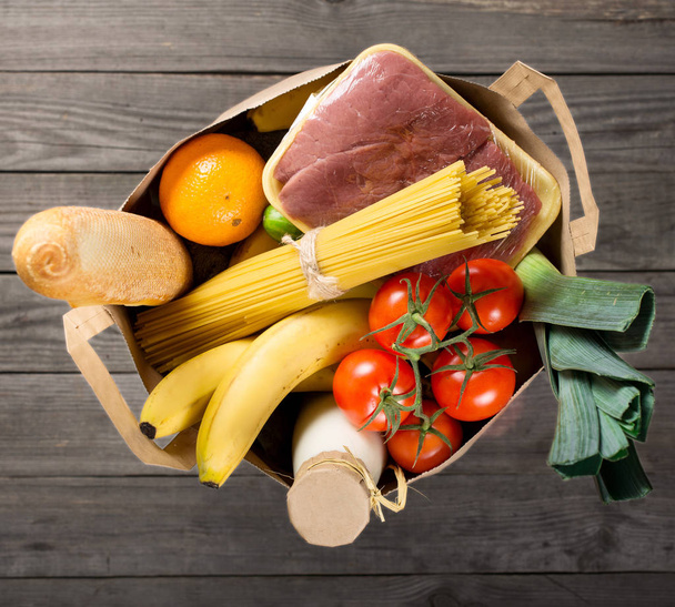 Full paper bag of various groceries on wooden background - Fotografie, Obrázek