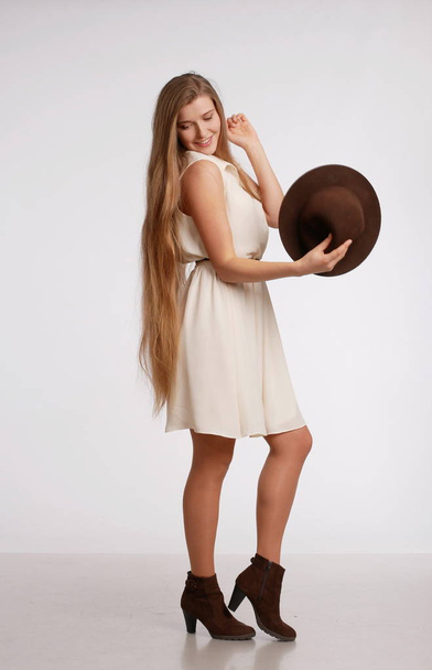 Girl in full growth in a dress above the knee with hat.  - Foto, imagen