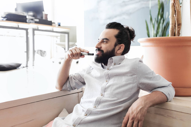 smiling man with beard and hair bun at office - Foto, afbeelding